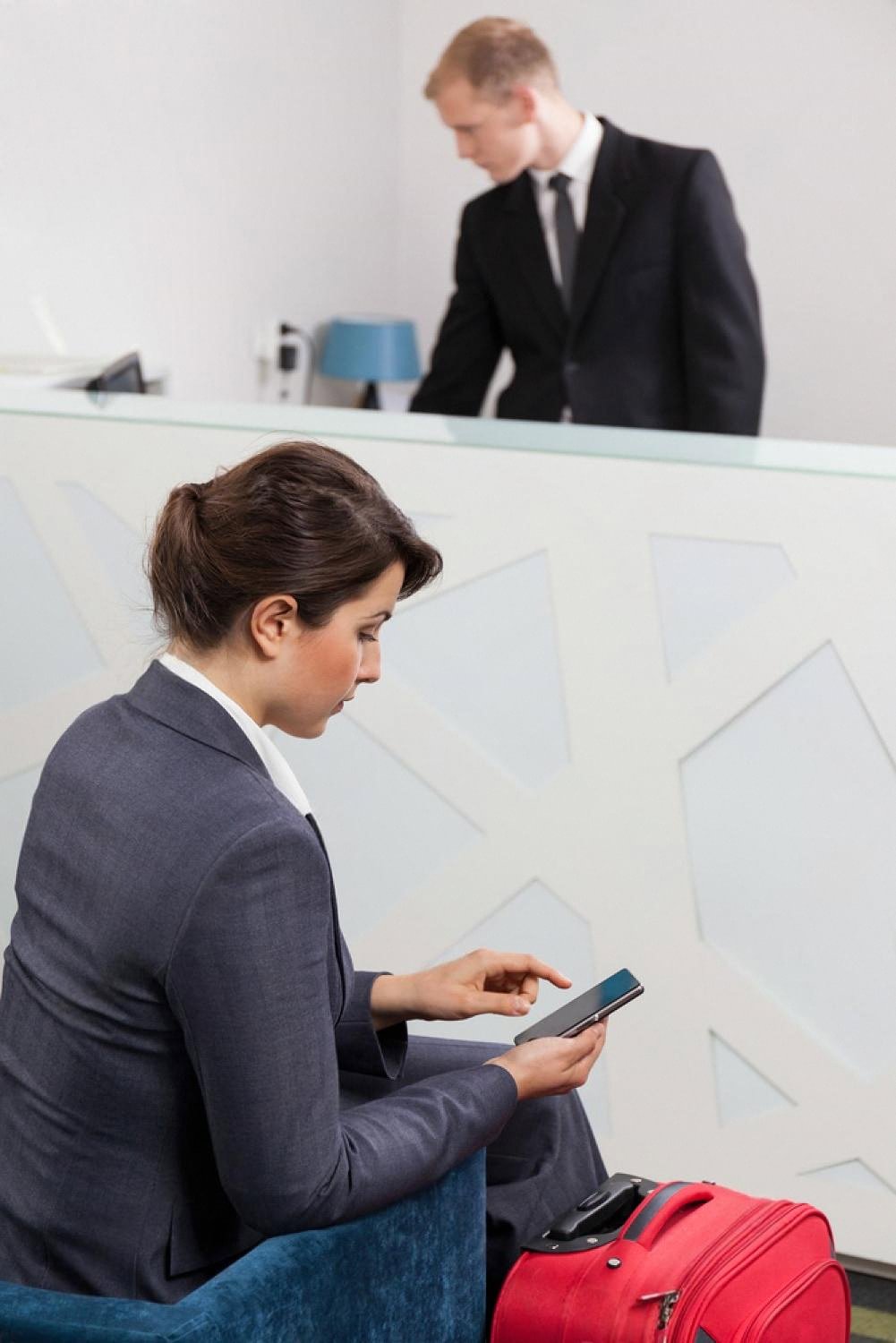 Guest waiting in a UAE hotel lobby while a receptionist works behind the front desk